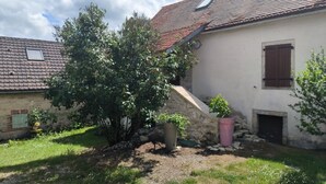 A house with a sloped roof, a small window, and a door. There is a tree in the front yard and a potted plant near the door. - Lot house in Bouriane (Thédirac)
