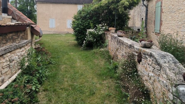 A stone wall, a grassy area, and a building with a tiled roof. - Lot house in Bouriane (Thédirac)