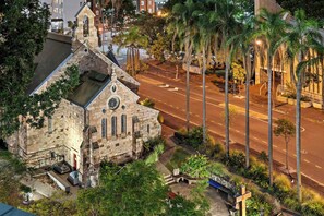A stone church with a bell tower, a paved road, and palm trees. - Stylish Apartment w/ Balcony, Pool & Gym (Brisbane City)