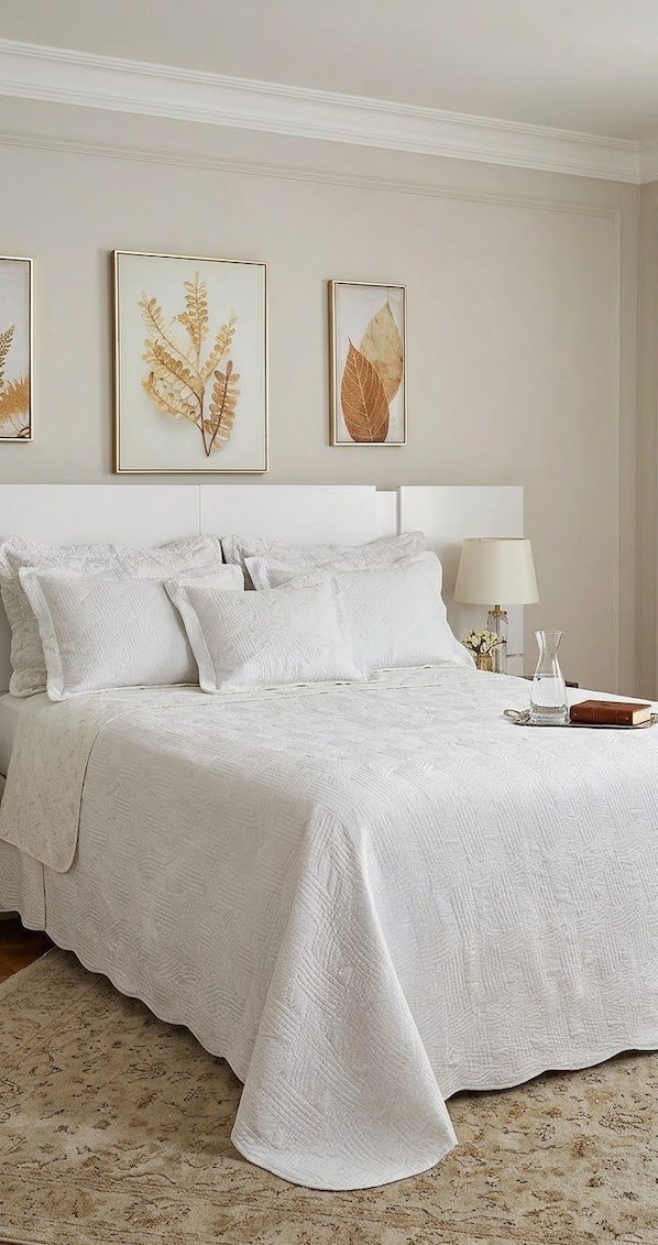 Un dormitorio con una cama grande, ropa de cama blanca, una mesita de noche con lámpara e impresiones botánicas enmarcadas en la pared.