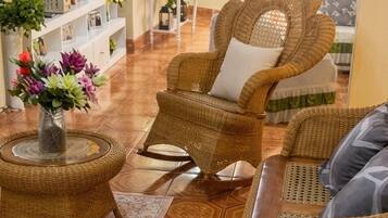 A living room with wicker furniture, a round coffee table, and a decorative vase with flowers.