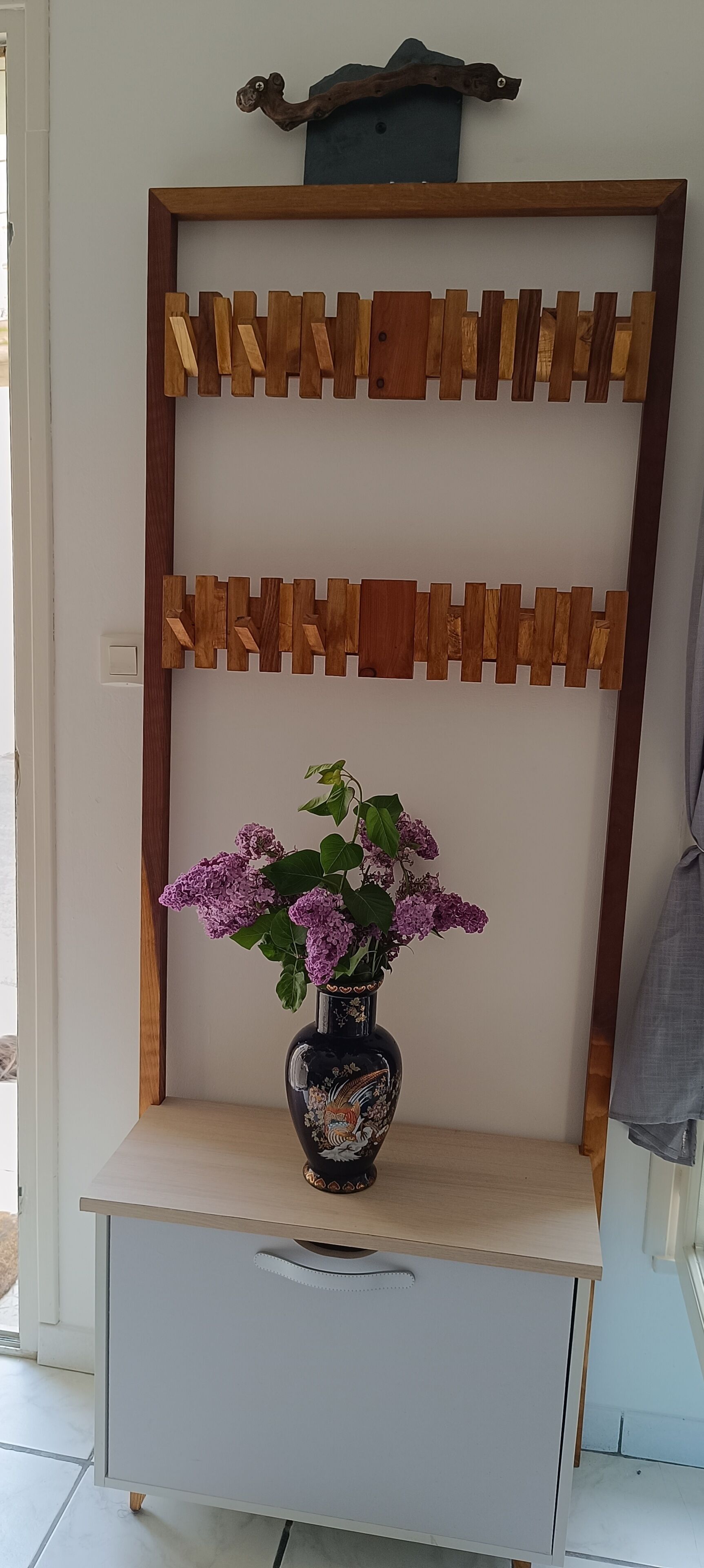 A wooden shelf with a vase of purple flowers.