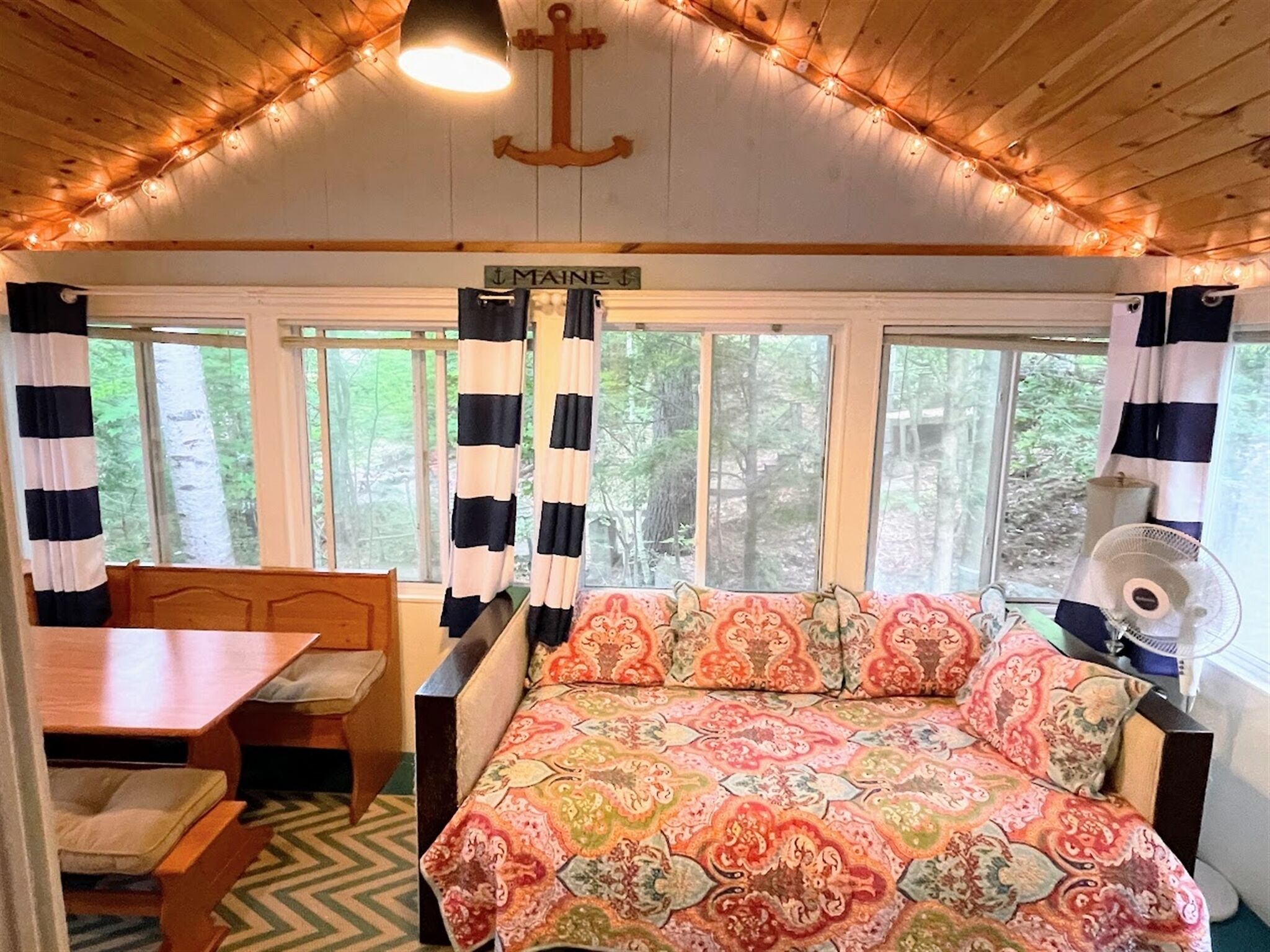 A cabin interior with a bed, a table, and a window with curtains.