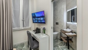 A modern bathroom with a large mirror, a sink, and a toilet. There is a TV mounted on the wall displaying a VIM app. - Adriana 5 Luxury rooms (Rome)