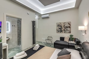 A modern hotel room with a bed, a seating area, a shower, and artwork on the walls. - Adriana 5 Luxury rooms (Rome)