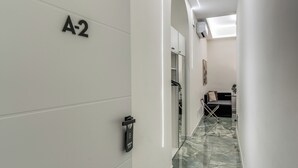 A hallway with a marble floor, a coat rack, a sofa, and a door labeled 'A-2'. - Adriana 5 Luxury rooms (Rome)
