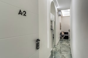 A hallway with a marble floor, a coat rack, a sofa, and a door labeled 'A-2'. - Adriana 5 Luxury rooms (Rome)