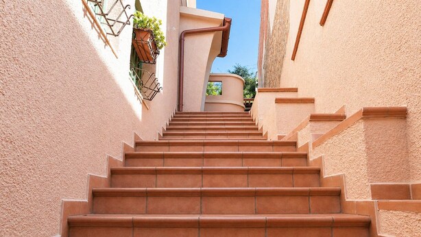 Eine Treppe führt in einem Gebäude mit Terrakotta-Stufen und beigen Wänden nach oben.