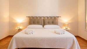 Ein Doppelbett mit Kopfstütze, zwei Nachttische mit Lampen und zusammengerollte Handtücher auf dem Bett.