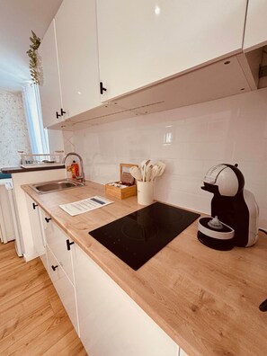 A modern kitchen with a wooden countertop, a built-in stove, a coffee machine, and a sink. - Marea Cosy Terrace All-Inclusive, Mourillon Center (Toulon)