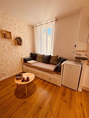 A compact living space with a sofa bed, a small table with a candle, and a compact refrigerator. - Marea Cosy Terrace All-Inclusive, Mourillon Center (Toulon)