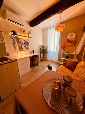 A compact living space with a kitchenette, a dining area, and a seating area with a sofa and a chair.