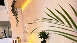 Un bureau blanc avec une plante en pot, un verre de jus de fruits et une lampe.
