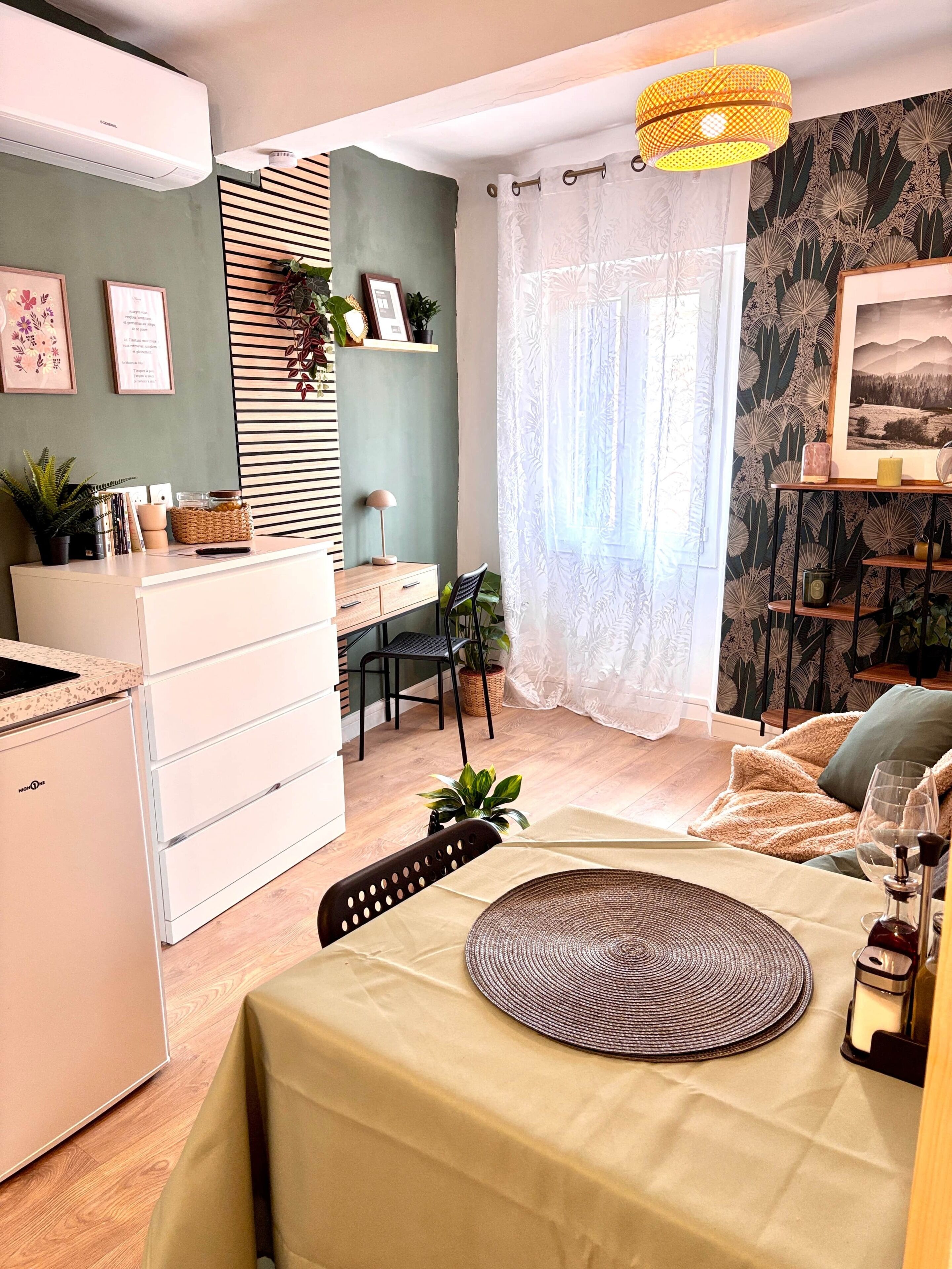 Een moderne keuken met een ingebouwde oven, een eethoek met een tafel gedekt voor twee personen, en een gezellige zithoek met een bank en een fauteuil.