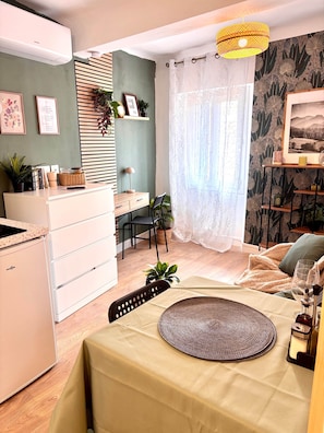 Moderni keittiö, jossa on sisäänrakennettu uuni, ruokailutila kahdelle katetulla pöydällä sekä viihtyisä oleskelualue, jossa on sohva ja nojatuoli.