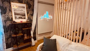 A cozy room with a bed, a wall-mounted projector, and a decorative screen.