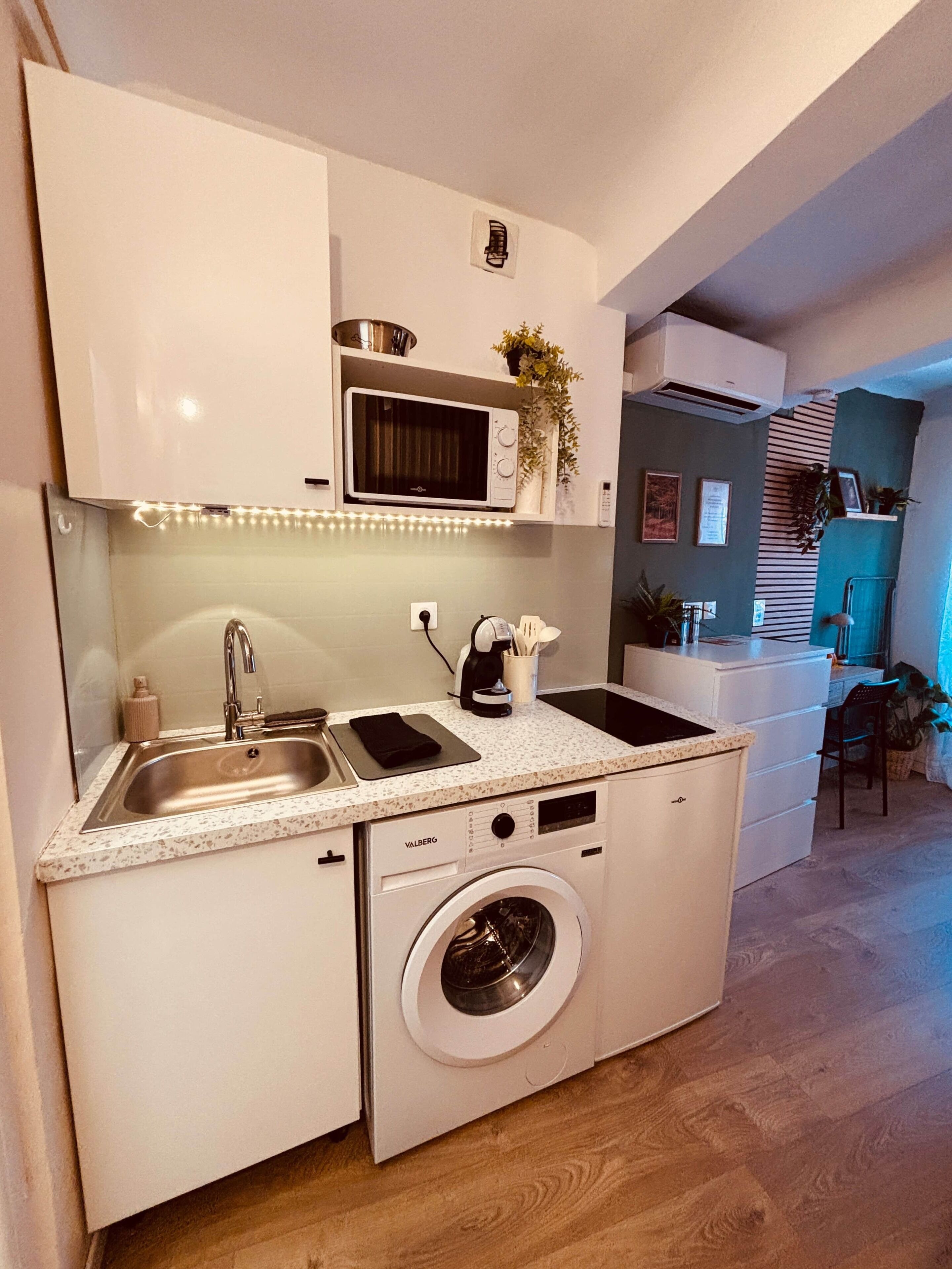 A compact kitchen with a washing machine, a microwave, and a sink.