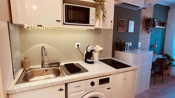 A compact kitchen with a washing machine, a microwave, and a sink.
