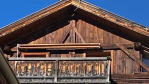 Un edificio de madera con balcón, varias ventanas y techo inclinado.