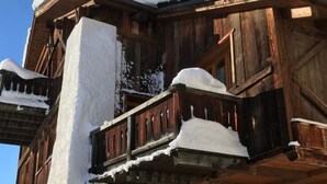 Un bâtiment en bois doté d’un balcon recouvert de neige, d’une porte en bois et d’une porte de garage.