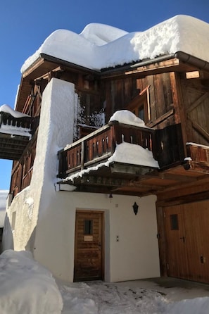 A wooden building with a balcony covered in snow, a wooden door, and a garage door. - Jassa Sura, (Tschlin) by Interhome (Tschlin)