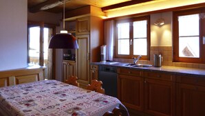Una cocina con armarios de madera, un lavamanos y un comedor con una mesa preparada para dos.
