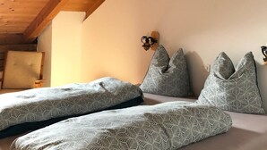Une chambre avec un plafond en bois, un lit recouvert d’une literie à motifs et un luminaire fixé au mur.