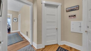 Un couloir aux murs de couleur beige, une porte blanche, une grille d’aération, un tableau encadré et un panneau indiquant qu’il est interdit de fumer.