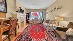 Un salon avec une cheminée, un canapé, un fauteuil, une table et un tapis rouge.