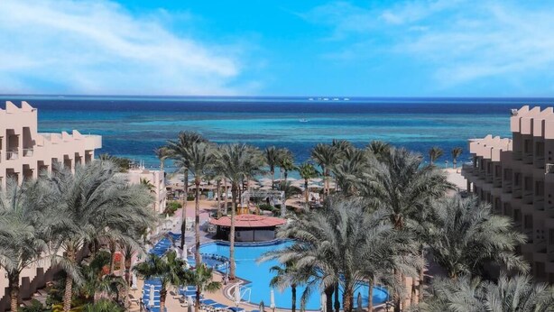 Un resort con piscina, palmeras y vista al océano.