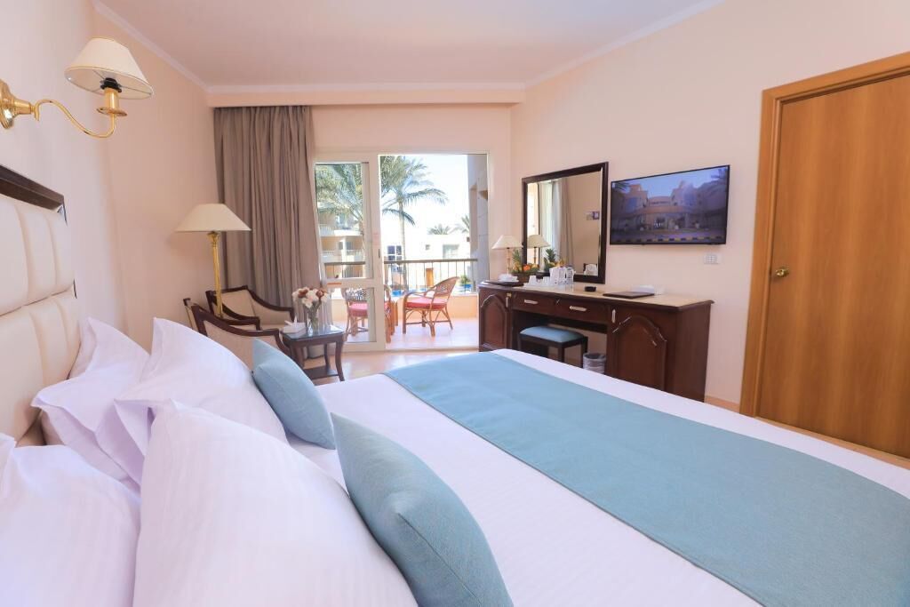 Ein Hotelzimmer mit Bett, Schreibtisch, Stuhl, Fernseher und einem Balkon mit Blick.
