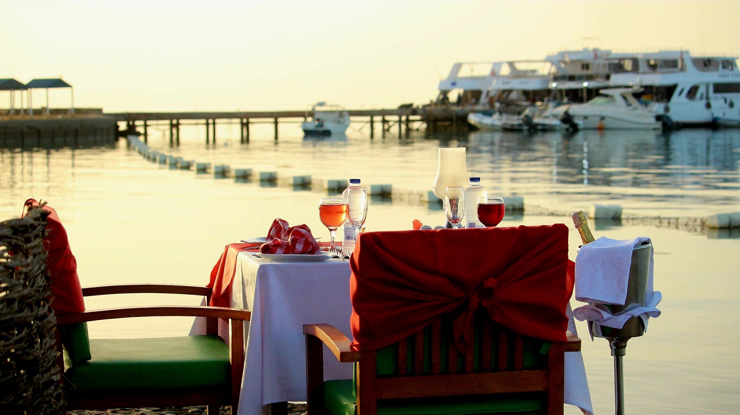 A table set for two with a view of boats and a pier in the background.