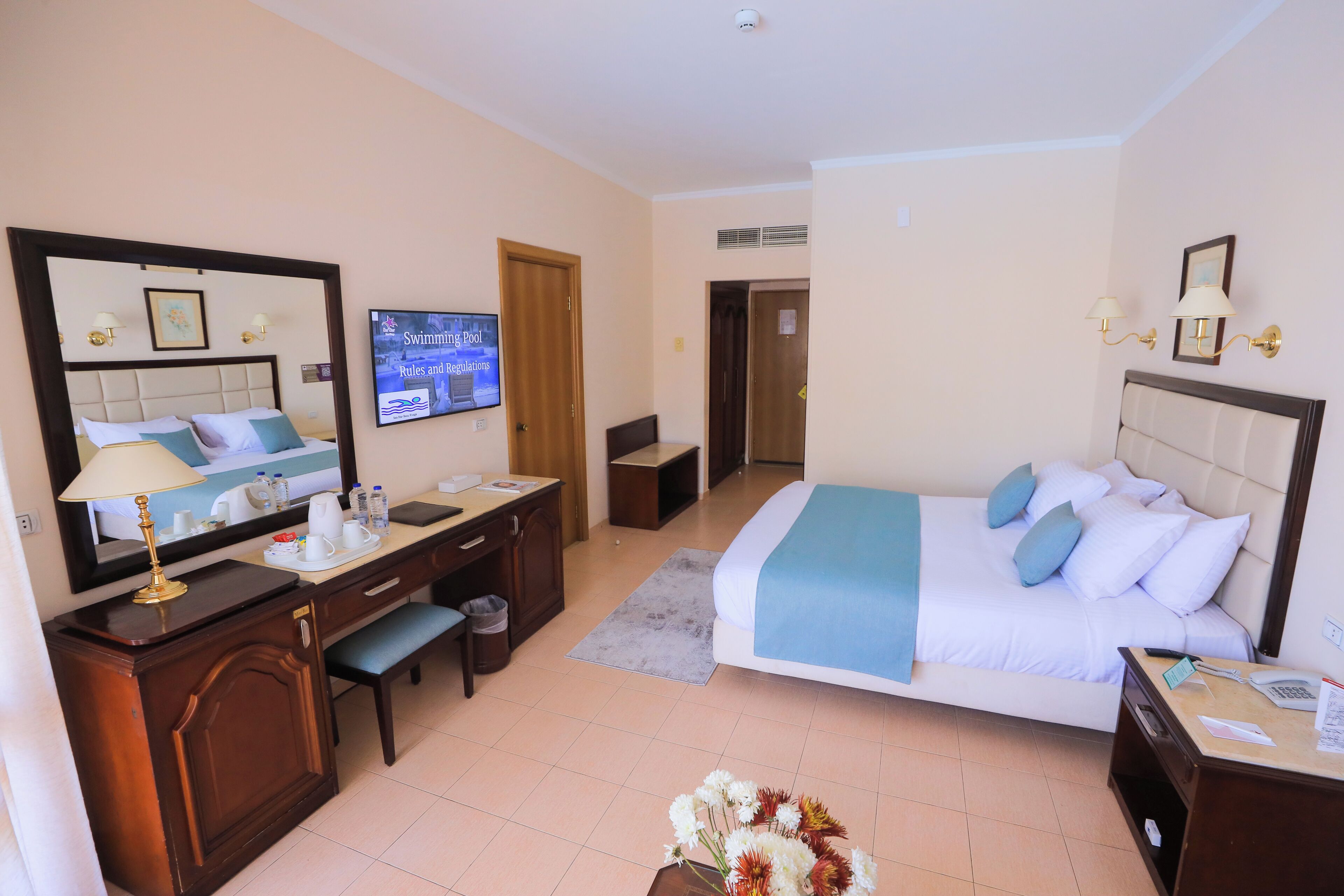 Una camera d'albergo con un letto, una scrivania, una sedia e un televisore appeso al muro.