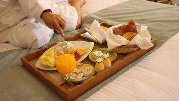 Bandeja de desayuno con huevos, jamón, queso y jugo sobre la cama.