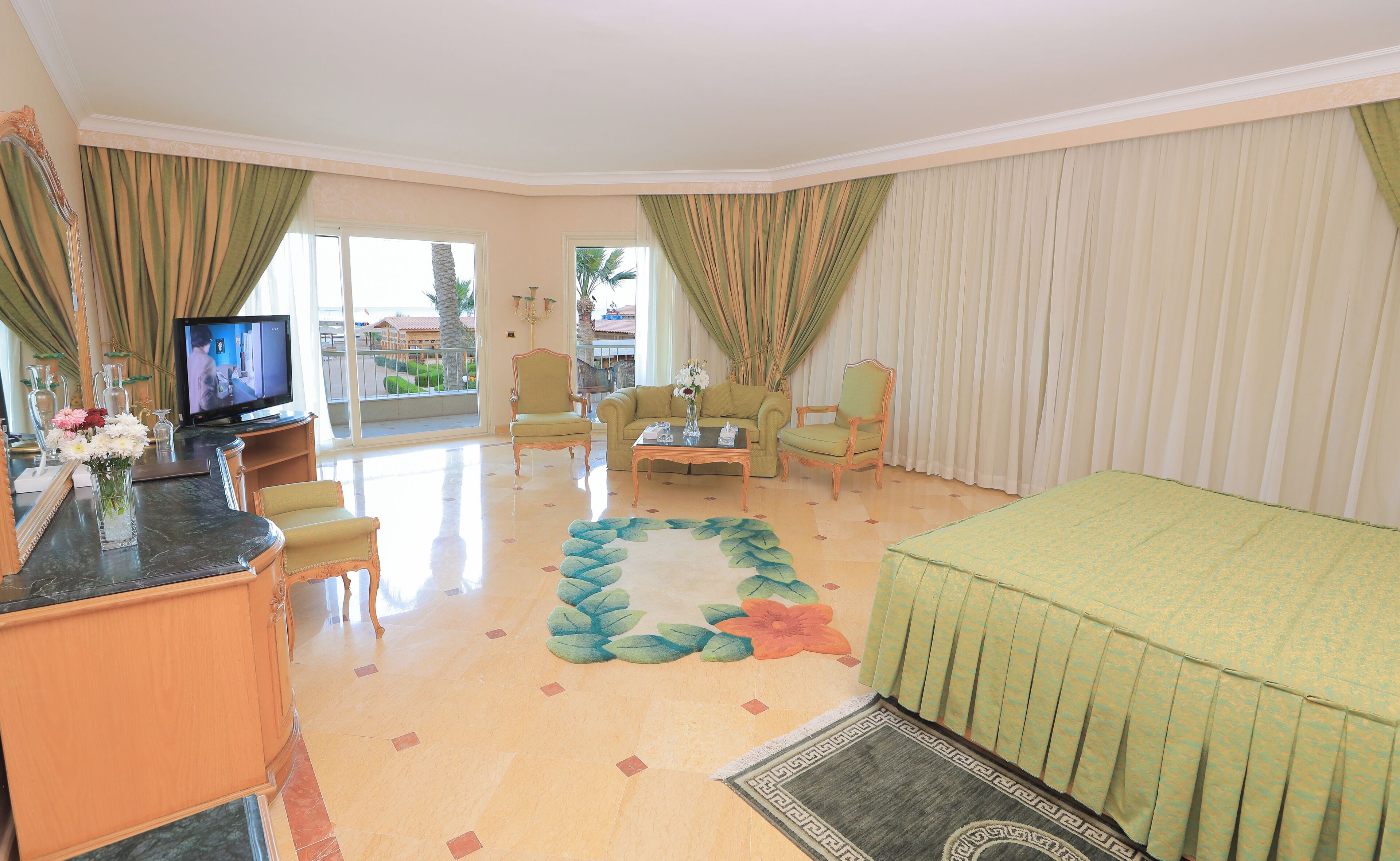 Une chambre d’hôtel avec un balcon, un canapé, une table basse et un téléviseur.