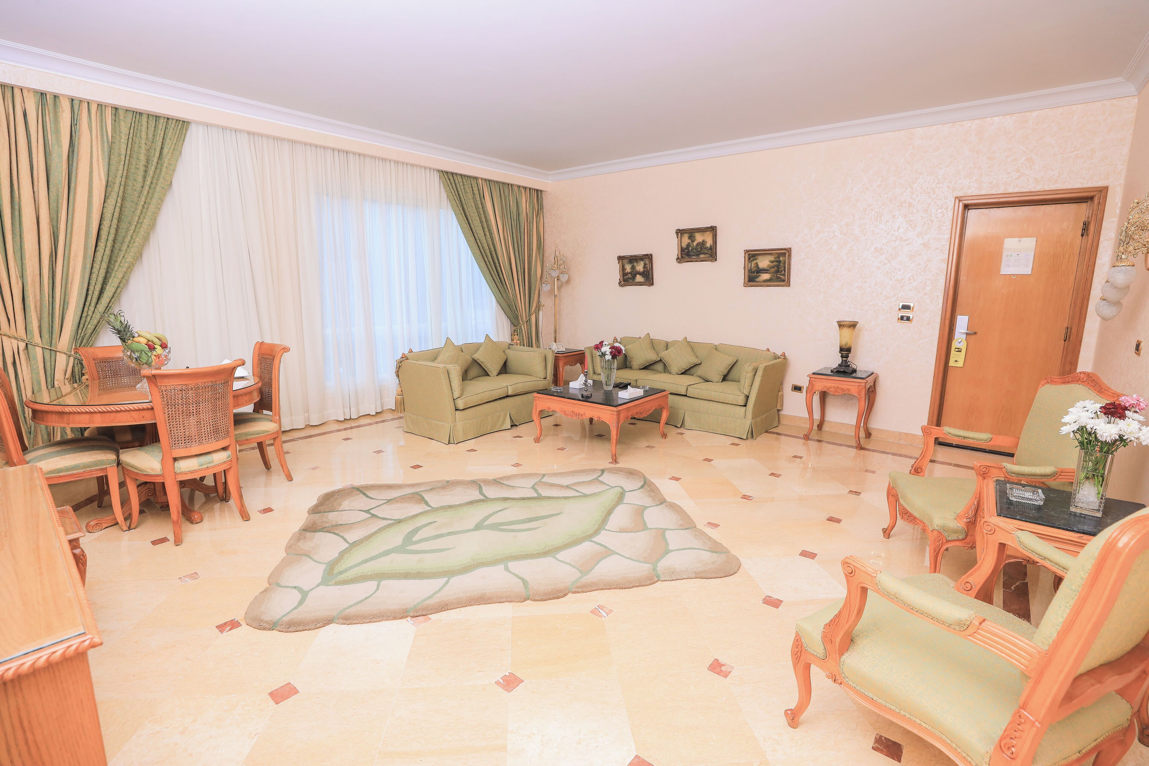 Una sala de estar con comedor, sofá verde, muebles de madera y un tapete decorativo.