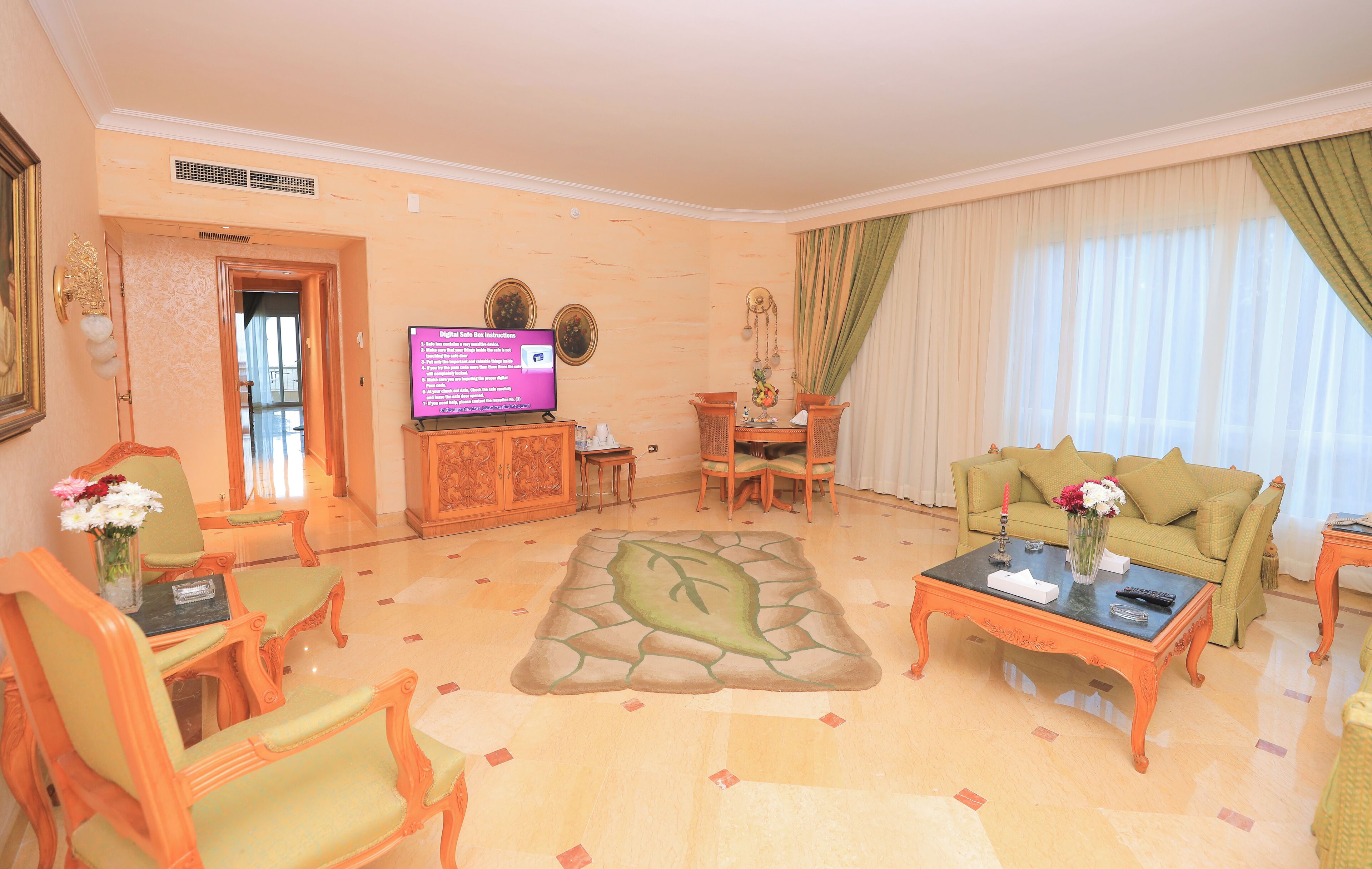 A living room with a television, a sofa, a coffee table, and a dining area.