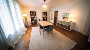 A dining area with a wooden table, chairs, a rug, and a pendant light.