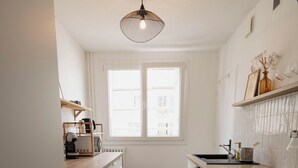 A narrow kitchen with white cabinetry, a wooden countertop, a built-in oven, and a window with blinds.