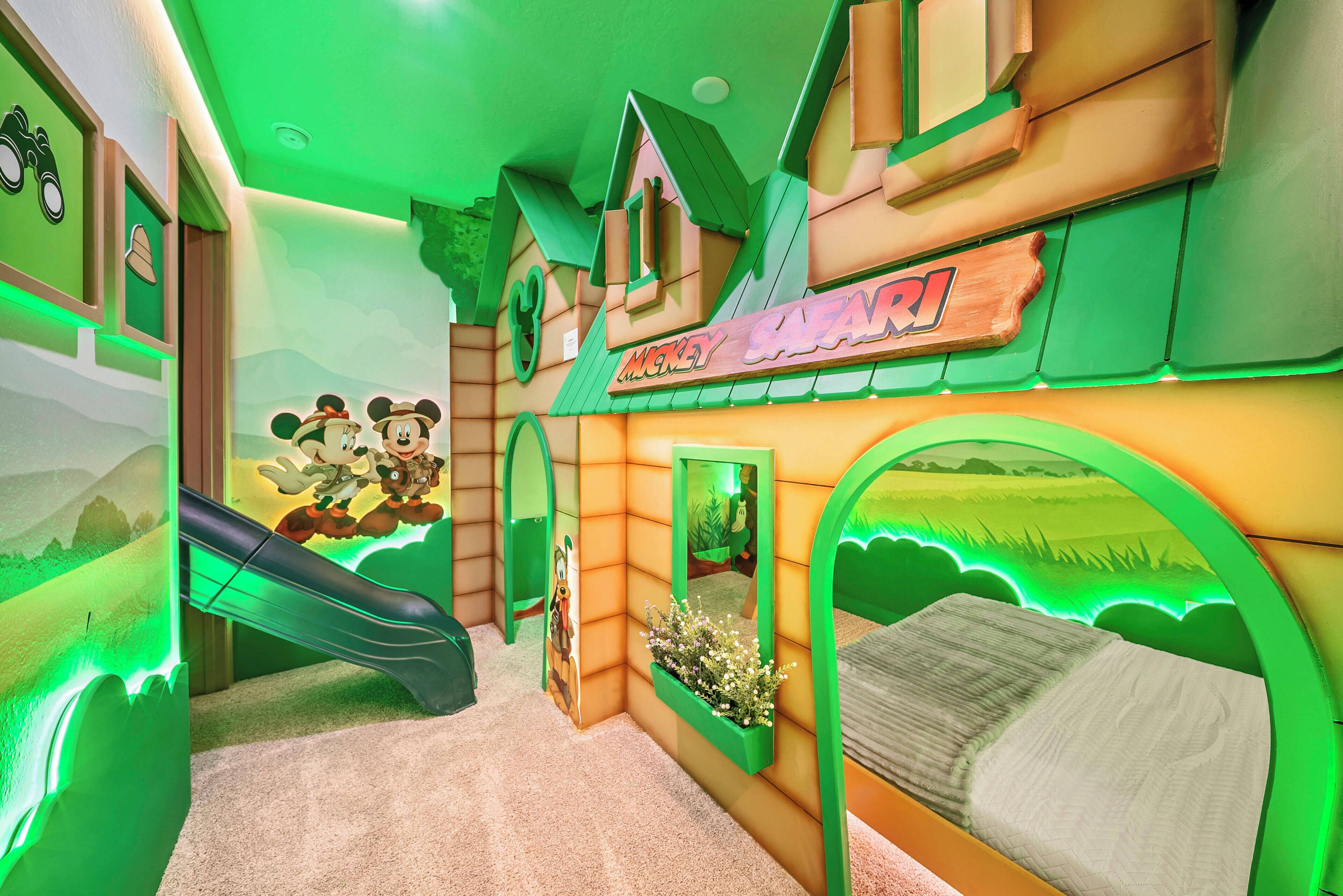This vibrant children's room boasts a playful treehouse design with bright green accents and whimsical art, promoting adventure. Cozy beds ensure restful nights, while the slide provides endless fun for your little ones.