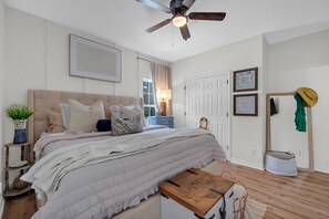 A bedroom with a bed, bedside table, ceiling fan, and a window with curtains. - Poolside Oasis-Sleeps 8 • 7-Min Walk to Beach • Fully renovated 3BR (Gulf Shores)
