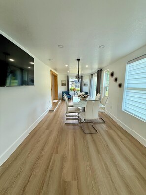 Ein modernes Interieur mit Essbereich, Holzböden und großen Fenstern.