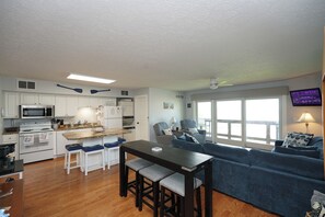 A compact kitchen with a dining area, a blue sofa, and a TV mounted on the wall. - Stay Here, Boat There- Walk to Jet + Pool & Beach (Port Clinton)