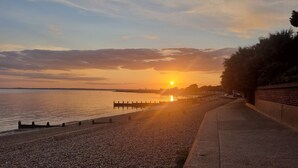 A sunset over a calm body of water with a promenade and distant city skyline. - Hill Head Beach-side Cottage with Hot Tub, Large Garden and Sea Views 5bed slp12 (Fareham)
