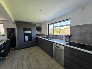 A modern kitchen with a built-in oven, a dishwasher, and a window providing a view of the outdoors.