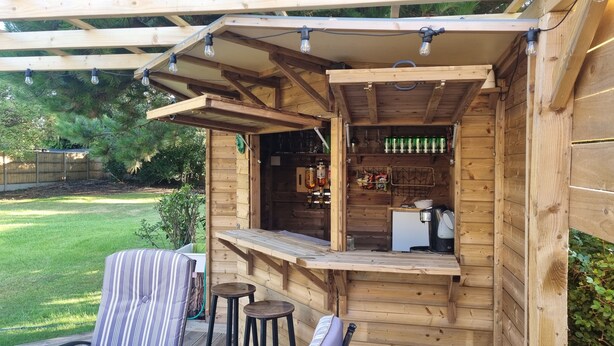A wooden outdoor bar area with a counter, stools, and a refrigerator. - Hill Head Beach-side Cottage with Hot Tub, Large Garden and Sea Views 5bed slp12 (Fareham)