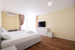 A hotel room with a bed, a flat-screen TV, a dresser, and a wooden floor. - Panoramic Sea-View Apartment, Durrës Promenade (Durrës)