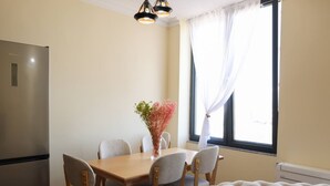 Un comedor con una mesa, sillas, un florero con flores, un sofá y una ventana con cortinas.