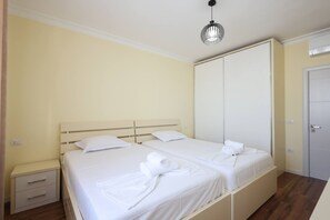 Une chambre d’hôtel avec deux lits, une armoire, une table de chevet et un luminaire suspendu.