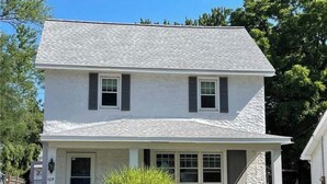 A two-story house with a front porch, a garage, and a well-maintained lawn.